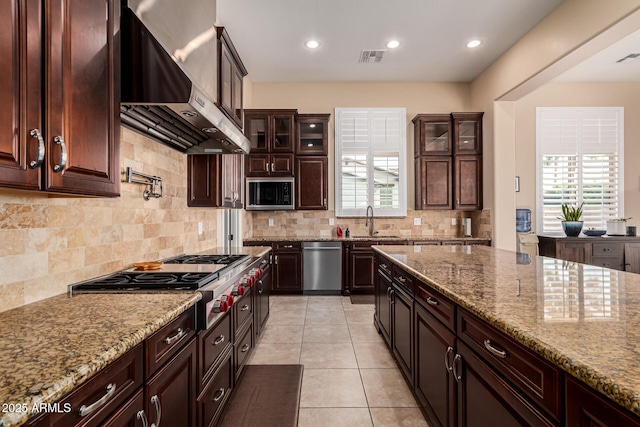 kitchen featuring sink, appliances with stainless steel finishes, tasteful backsplash, light stone counters, and wall chimney exhaust hood