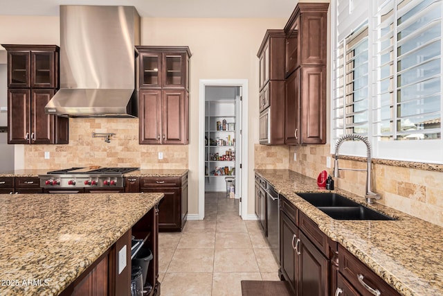 kitchen featuring light stone counters, sink, a healthy amount of sunlight, and wall chimney exhaust hood