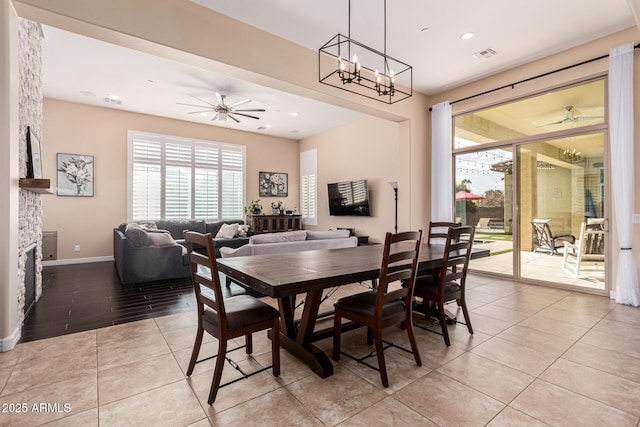 tiled dining area featuring plenty of natural light, a fireplace, and ceiling fan