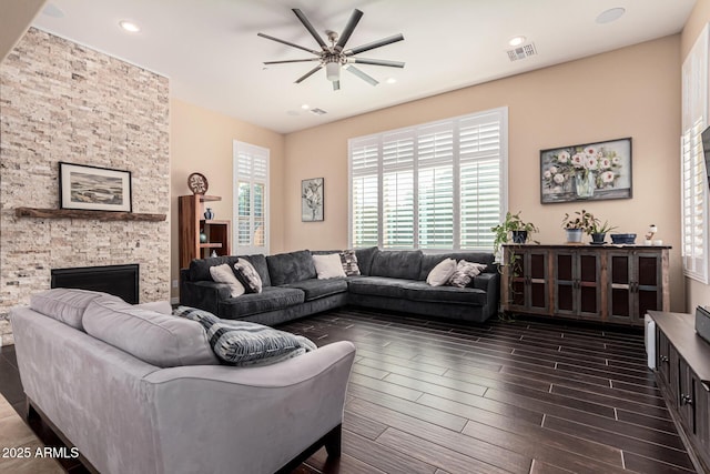 living room with dark hardwood / wood-style floors, ceiling fan, a healthy amount of sunlight, and a fireplace