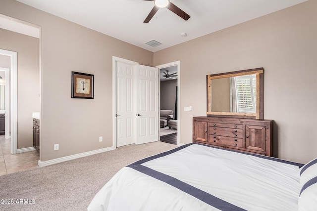 bedroom with ensuite bath, light colored carpet, ceiling fan, and a closet