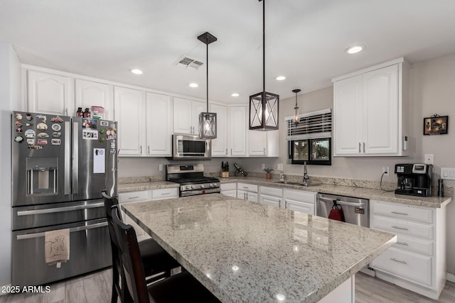 kitchen with a sink, visible vents, light stone counters, and appliances with stainless steel finishes