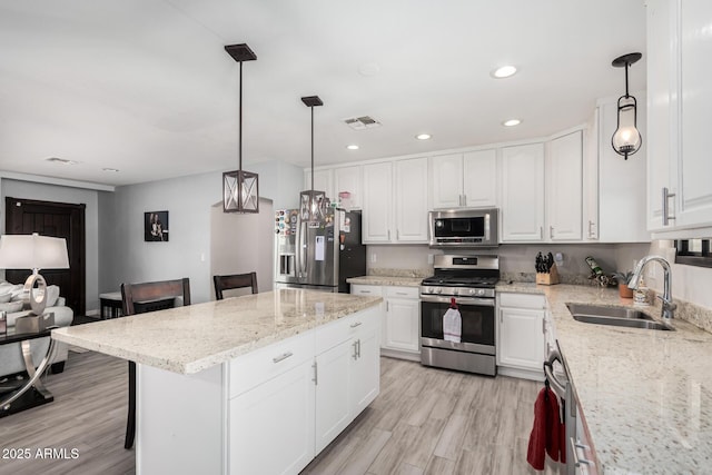kitchen featuring white cabinetry, a sink, light wood finished floors, visible vents, and appliances with stainless steel finishes