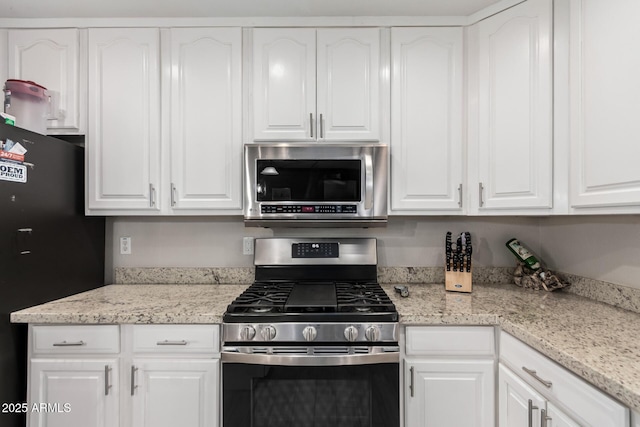 kitchen with white cabinetry, appliances with stainless steel finishes, and light stone counters