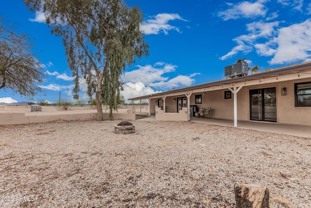 rear view of property featuring central AC unit, an outdoor fire pit, stucco siding, and a patio area