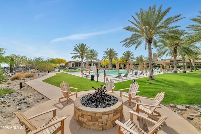view of community with a pool, a yard, a patio area, and an outdoor fire pit
