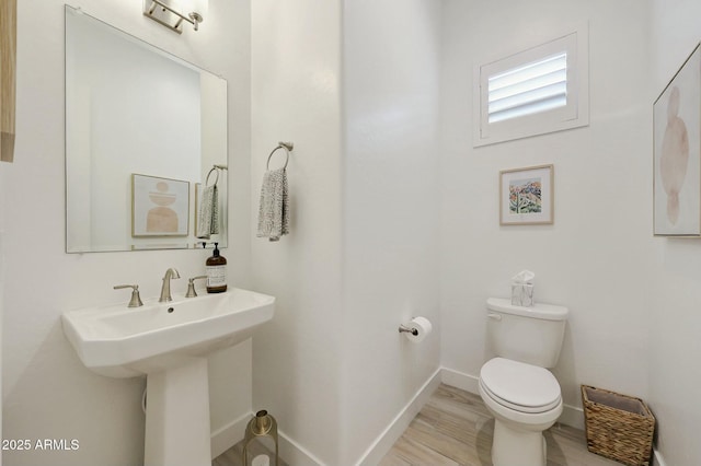 half bath with toilet, a sink, and baseboards