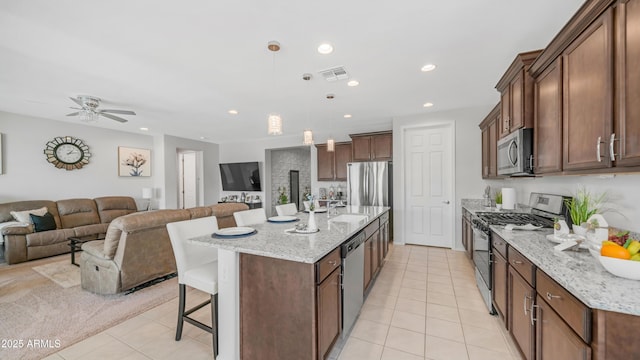 27636 W Runion Dr, Buckeye, AZ 85396 - kitchen with stainless steel appliances, open floor plan, a breakfast bar, light tile patterned flooring, and a sink