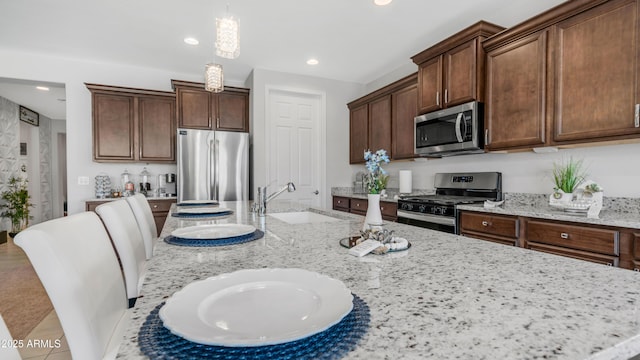 27636 W Runion Dr, Buckeye, AZ 85396 - kitchen featuring stainless steel appliances, a sink, hanging light fixtures, light stone countertops, and recessed lighting