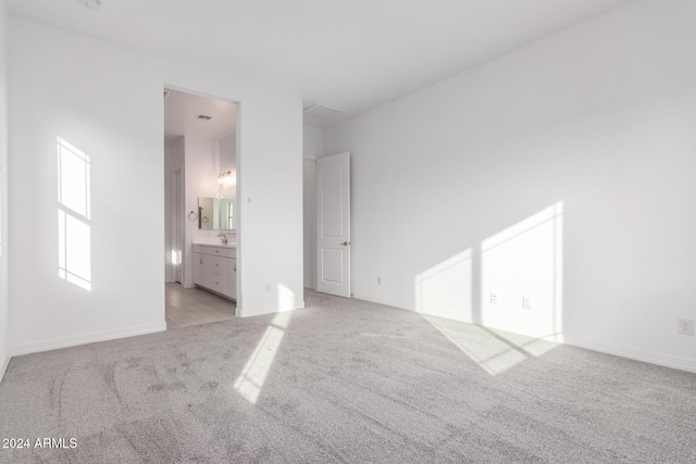 unfurnished bedroom featuring light colored carpet and connected bathroom