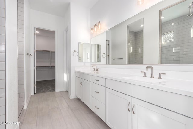 bathroom with hardwood / wood-style floors, tiled shower, and vanity