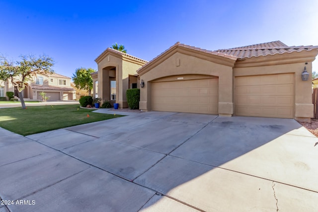 mediterranean / spanish home featuring a front yard and a garage