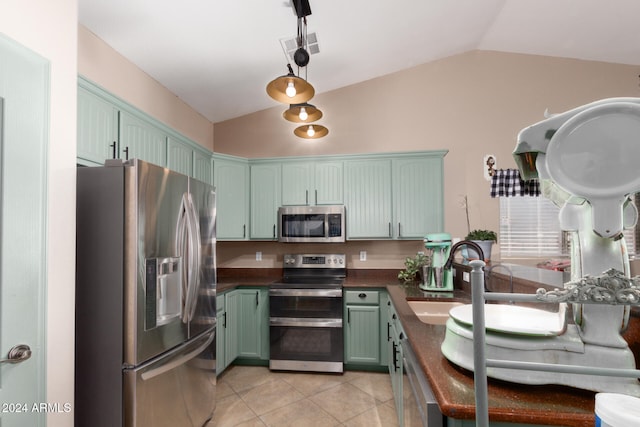 kitchen with appliances with stainless steel finishes, light tile patterned floors, vaulted ceiling, and sink