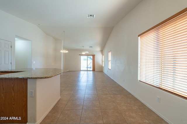 empty room with vaulted ceiling and light tile patterned floors