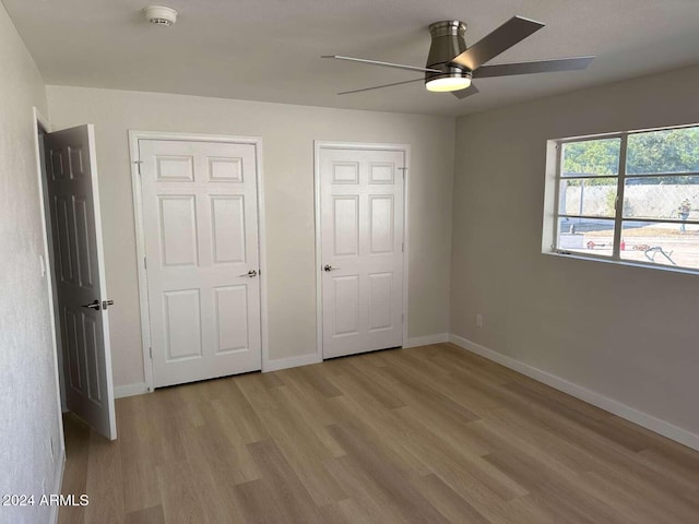 unfurnished bedroom with multiple closets, light hardwood / wood-style floors, and ceiling fan