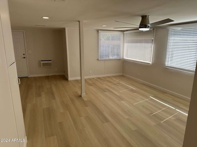 empty room featuring a wealth of natural light, a wall mounted AC, light hardwood / wood-style flooring, and ceiling fan