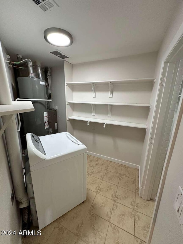 washroom featuring washer / dryer, water heater, and light tile patterned floors