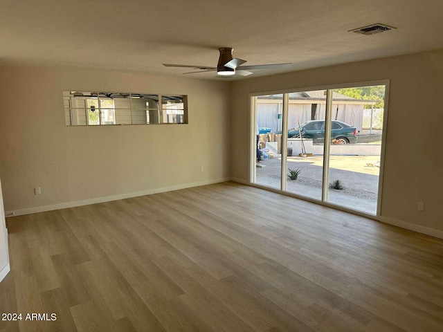 empty room with a wealth of natural light, light hardwood / wood-style floors, and ceiling fan