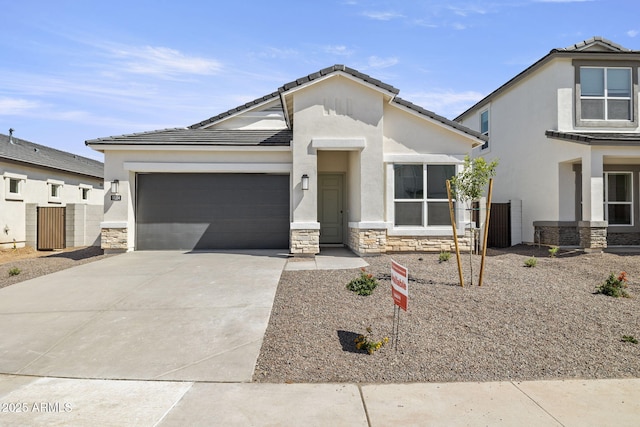 view of front of house featuring an attached garage, a tile roof, driveway, stone siding, and stucco siding