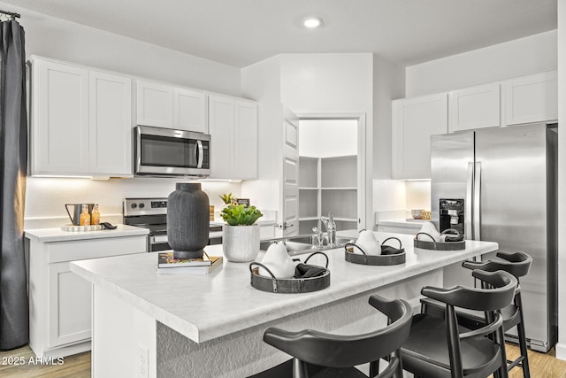 kitchen featuring stainless steel appliances, light countertops, and white cabinetry