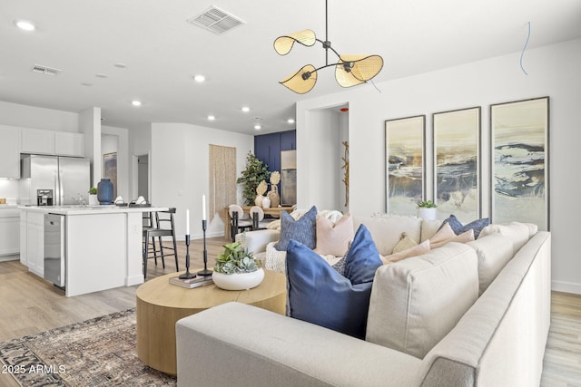 living area featuring light wood finished floors, baseboards, visible vents, and recessed lighting