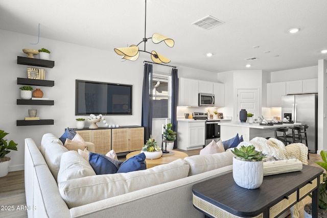 living room featuring light wood-style floors, recessed lighting, visible vents, and baseboards