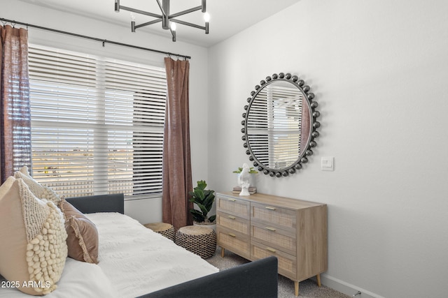 carpeted bedroom featuring baseboards and a notable chandelier