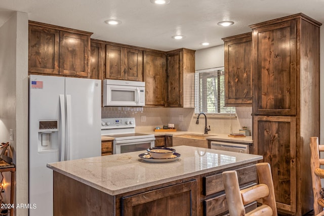 kitchen with backsplash, a center island, light stone countertops, sink, and white appliances