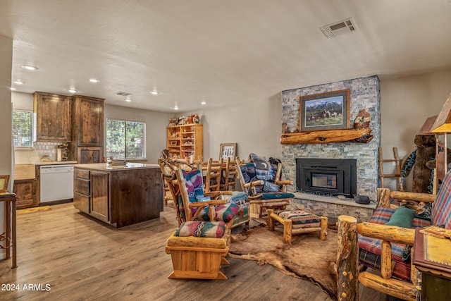 living room with a stone fireplace and light hardwood / wood-style flooring