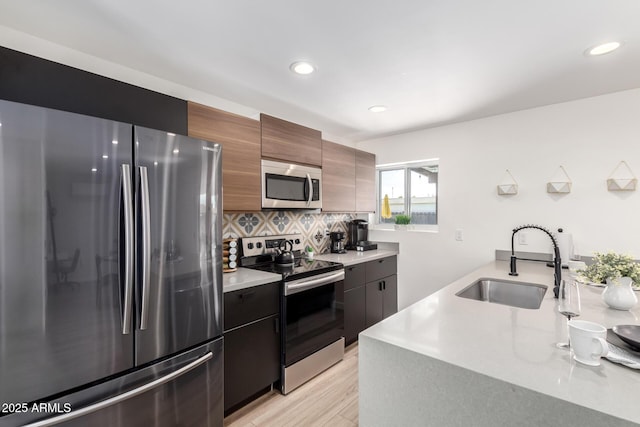 kitchen featuring tasteful backsplash, appliances with stainless steel finishes, sink, and light hardwood / wood-style flooring