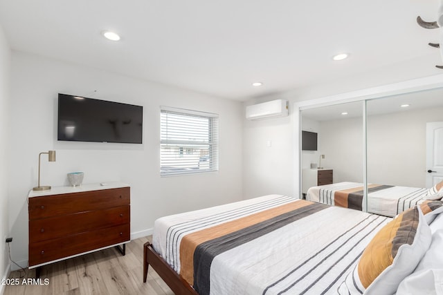 bedroom featuring a closet, a wall unit AC, and light hardwood / wood-style floors