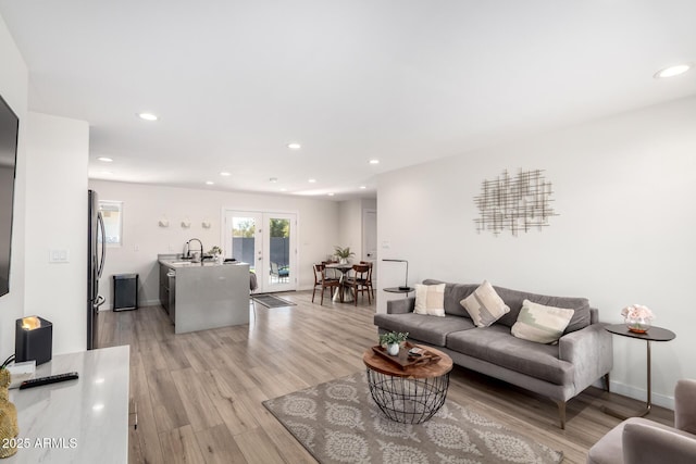 living room with french doors, sink, and light hardwood / wood-style flooring