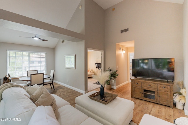 living room featuring ceiling fan, light hardwood / wood-style floors, and high vaulted ceiling