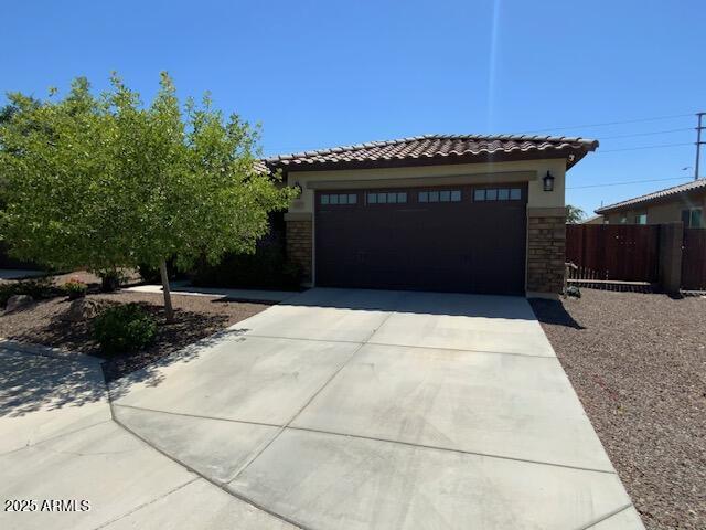 8587 N 171st Dr, Waddell, AZ 85355 - view of front of house featuring a tile roof, stone siding, concrete driveway, stucco siding, and an attached garage