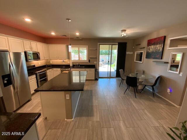8587 N 171st Dr, Waddell, AZ 85355 - kitchen with stainless steel appliances, white cabinets, recessed lighting, dark countertops, and hanging light fixtures