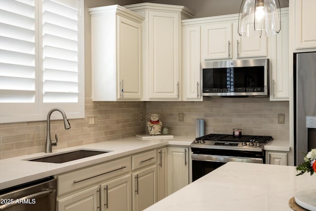 kitchen featuring light stone countertops, white cabinets, appliances with stainless steel finishes, a sink, and backsplash