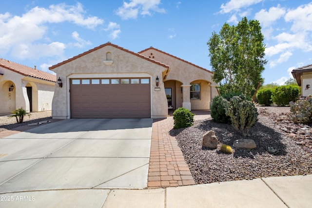 mediterranean / spanish home featuring a tile roof, driveway, a garage, and stucco siding