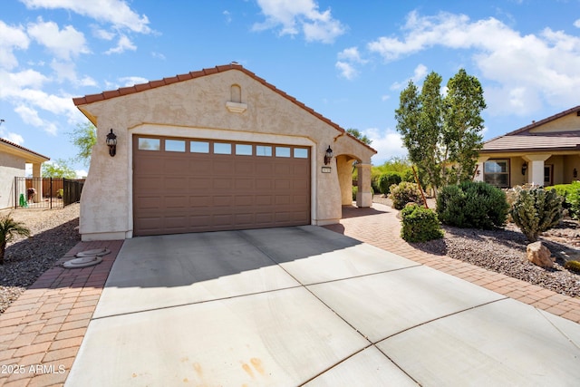 mediterranean / spanish home with concrete driveway, stucco siding, an outbuilding, a garage, and fence
