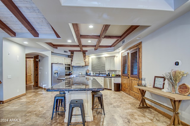 kitchen featuring a breakfast bar area, backsplash, beamed ceiling, stainless steel appliances, and a center island