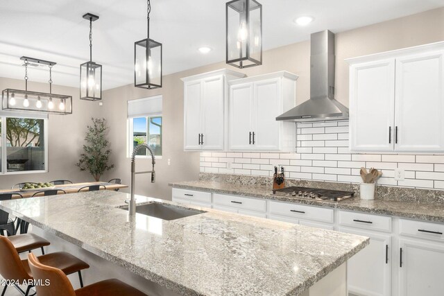 kitchen with white cabinets, stainless steel gas stovetop, and wall chimney range hood