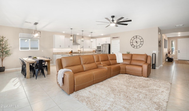 living room with a wealth of natural light, light tile patterned floors, and ceiling fan