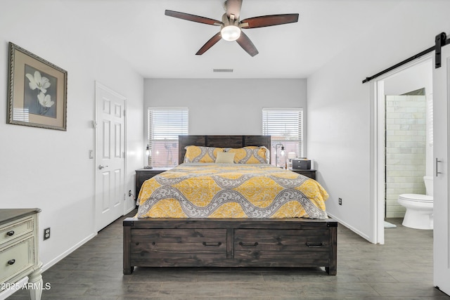 bedroom with dark hardwood / wood-style floors, a barn door, and multiple windows