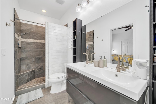 bathroom featuring vanity, toilet, and a tile shower