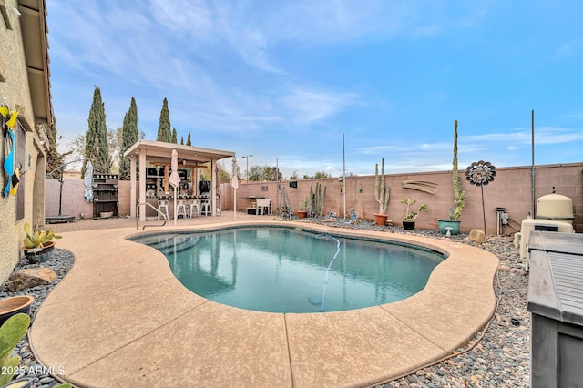 view of swimming pool featuring a patio, an outdoor kitchen, and a bar