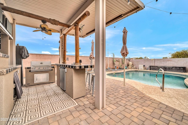 exterior space with exterior kitchen, grilling area, a bar, ceiling fan, and a fenced in pool