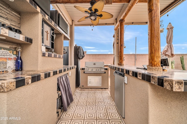 view of patio / terrace with area for grilling, ceiling fan, and an outdoor kitchen