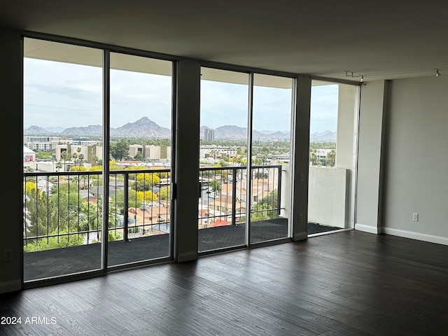 unfurnished room with a mountain view, dark hardwood / wood-style floors, and a wall of windows