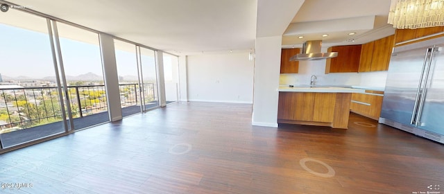 kitchen featuring backsplash, wall chimney exhaust hood, dark wood-type flooring, a wall of windows, and built in fridge