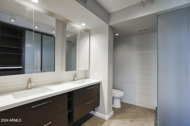 bathroom with vanity, toilet, and tile walls