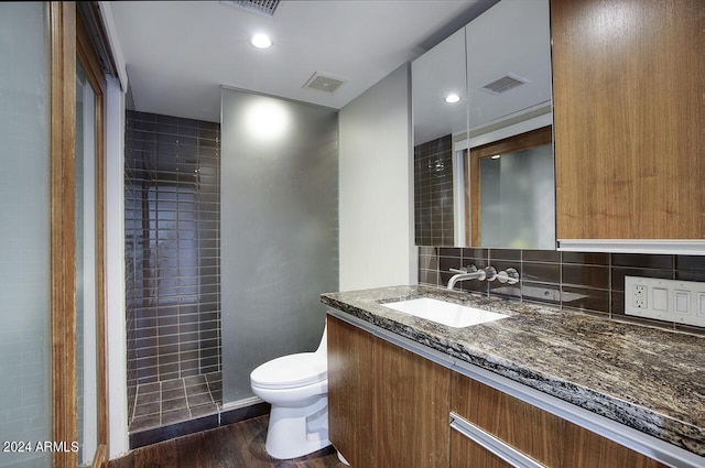 bathroom featuring tasteful backsplash, walk in shower, vanity, wood-type flooring, and toilet